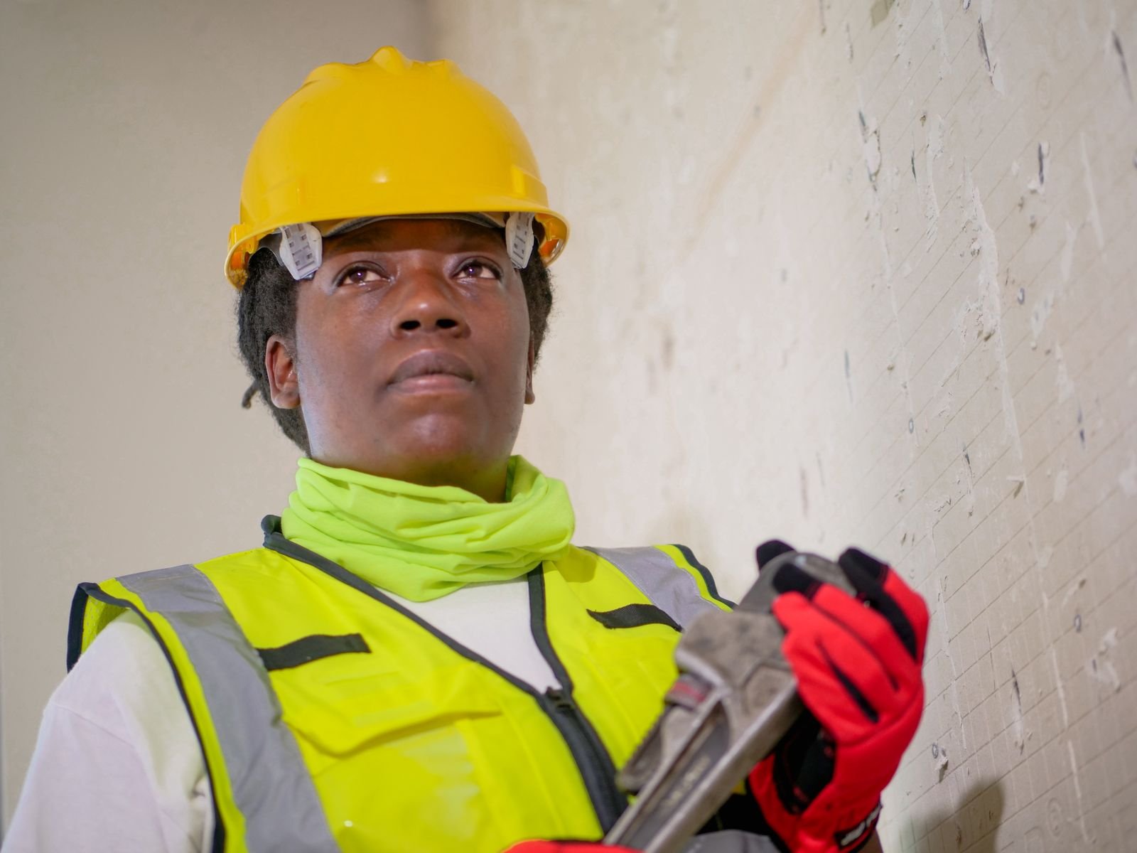 Professional plumbing technician in safety gear holding a wrench