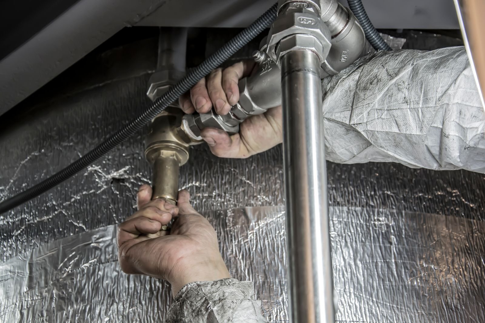 Plumber's hands installing steel pipes during a residential plumbing job