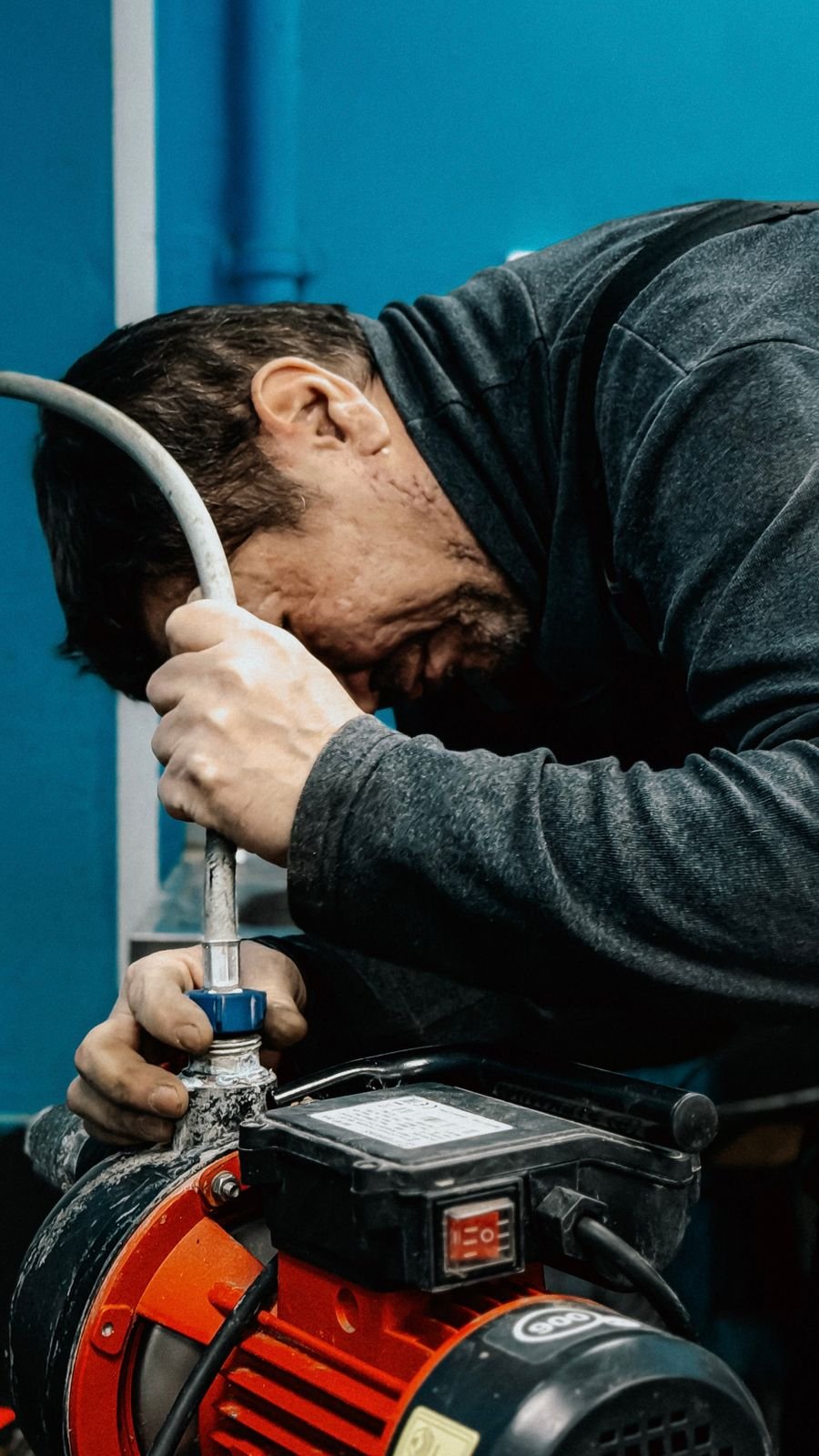 Licensed plumber servicing a residential water heater and pump assembly